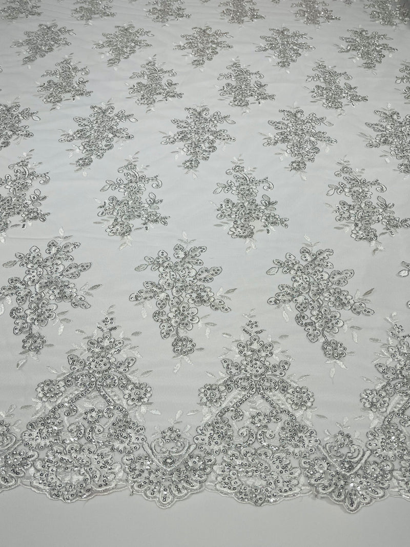 White Metallic floral design embroidery on a mesh lace with sequins and cord-sold by the yard.