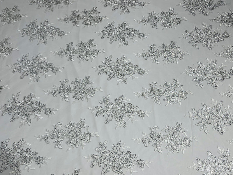 White Metallic floral design embroidery on a mesh lace with sequins and cord-sold by the yard.