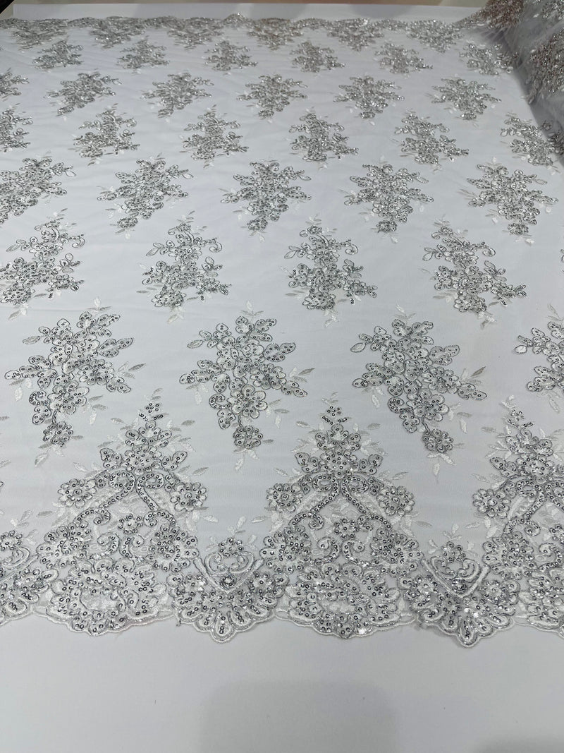 White Metallic floral design embroidery on a mesh lace with sequins and cord-sold by the yard.