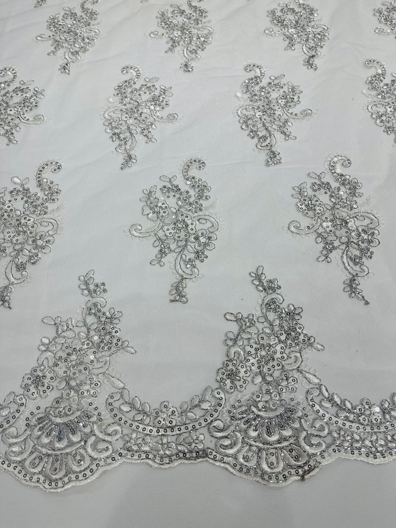 White/ silver metallic floral design embroidery on a mesh lace with sequins and cord-sold by the yard.