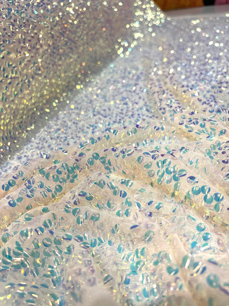 Aqua Clear iridescent mini round paillette sequins on a nude stretch mesh, sold by the yard.